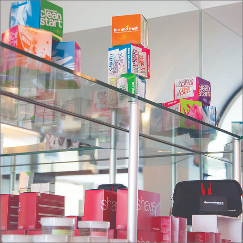 Glass display shelving unit supported by brushed metal standoff pillars.