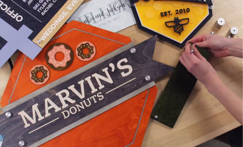 Assorted custom signs and materials for different industries on a workbench