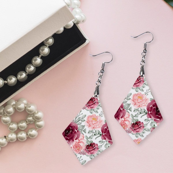 Earrings with flower design next to a string of pearls