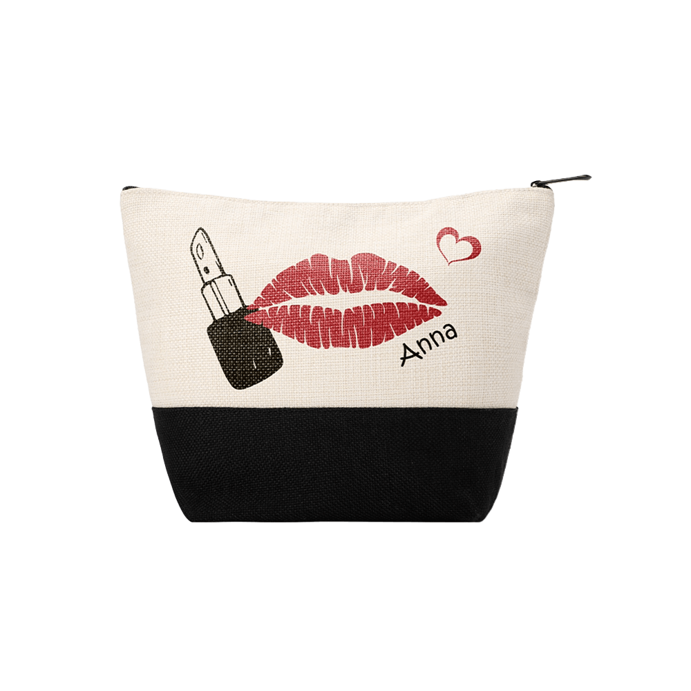 A personalized makeup pouch with a black and beige design. It features a print of red lipstick lips, a lipstick tube, and a small red heart with the name "Anna" written underneath.