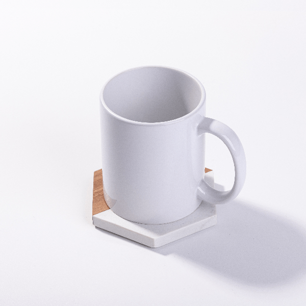 white mug sitting on hexagon white marble and acacia wood coaster