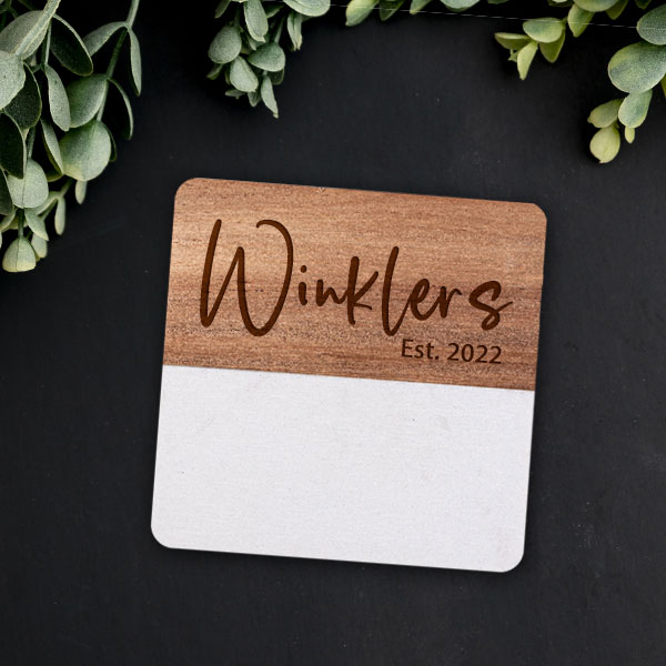 Lifestyle photo of square marble and wood coaster with radius corners engraved with name "Wrinklers"