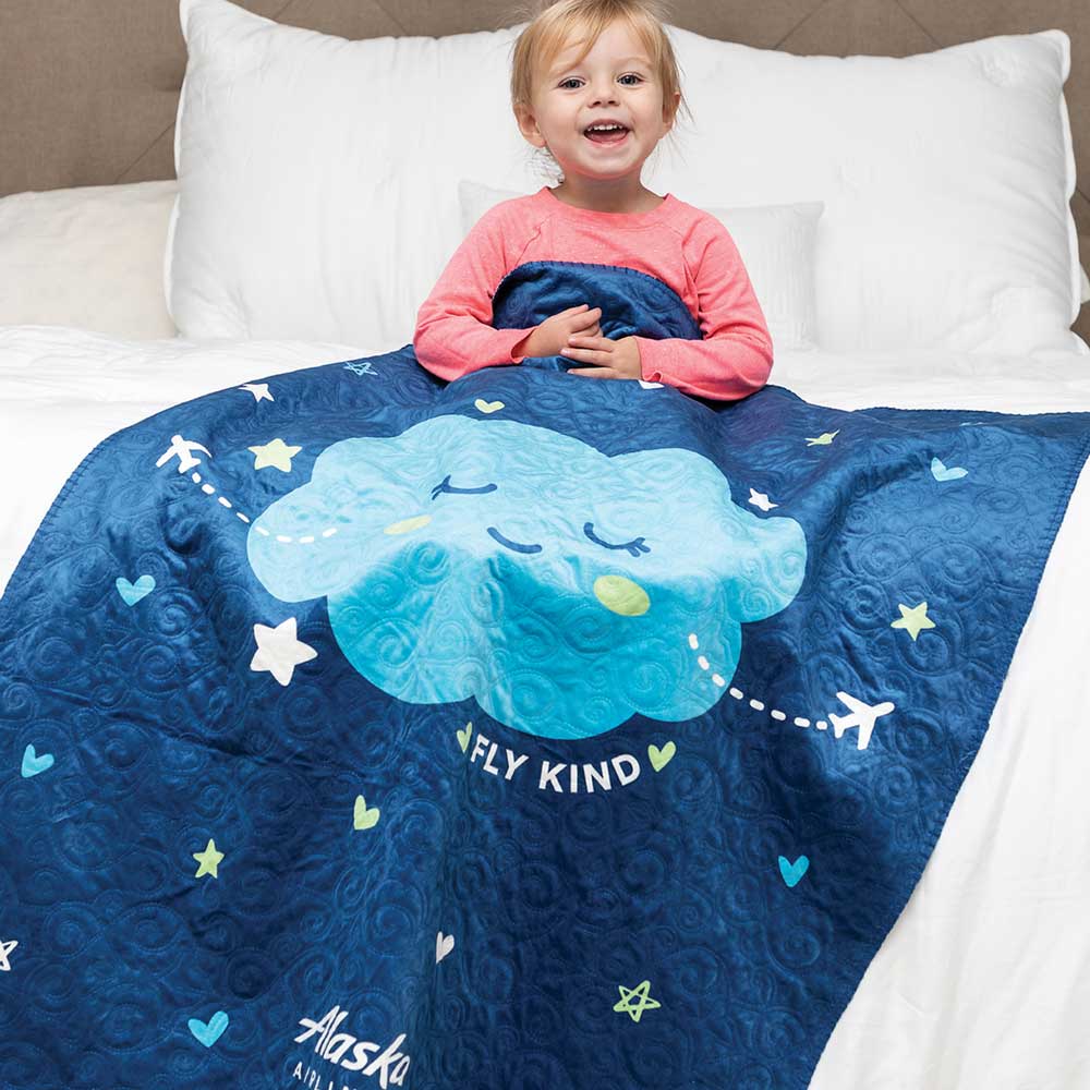Girl sitting under quilted baby blanket