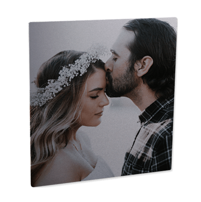 Man kissing woman's forehead on silver photo panel