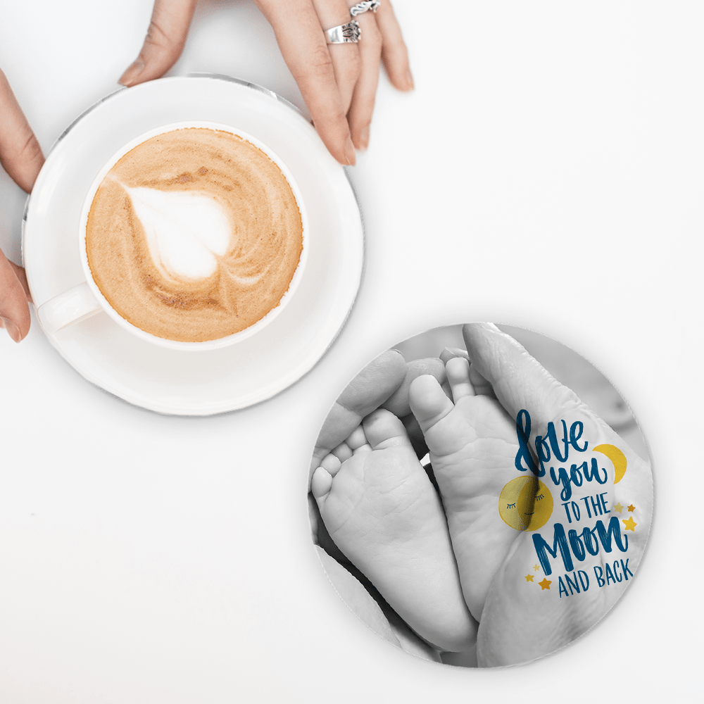 Round coaster with baby feet image sublimated next to coffee cup