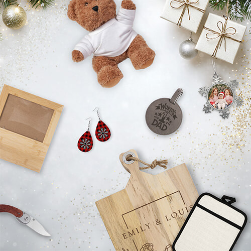 Holiday gifts on a white background, including a teddy bear, engraved cutting board, earrings, photo ornament, wooden frame, leather tag, and tumbler sleeve with festive decorations.